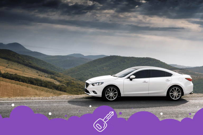 a white car on a road with hills in the background