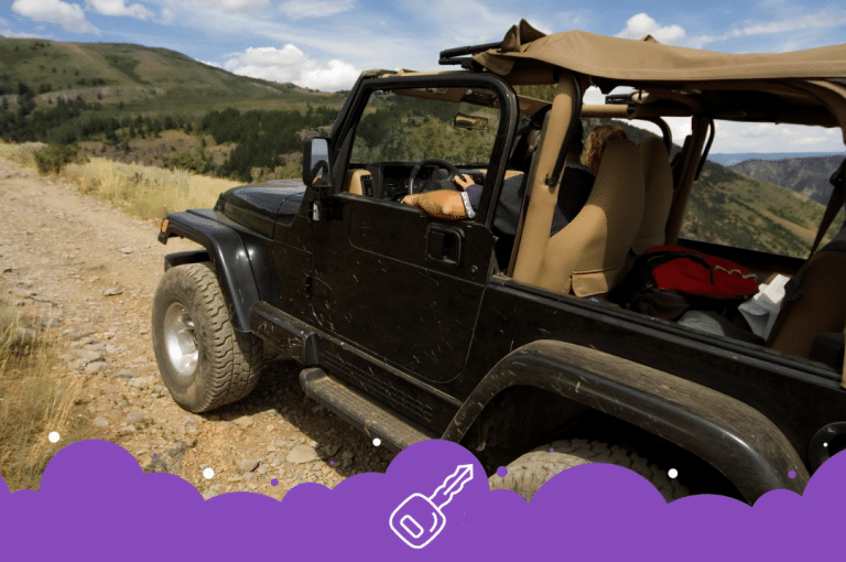 Black jeep wrangler driving up a mountain