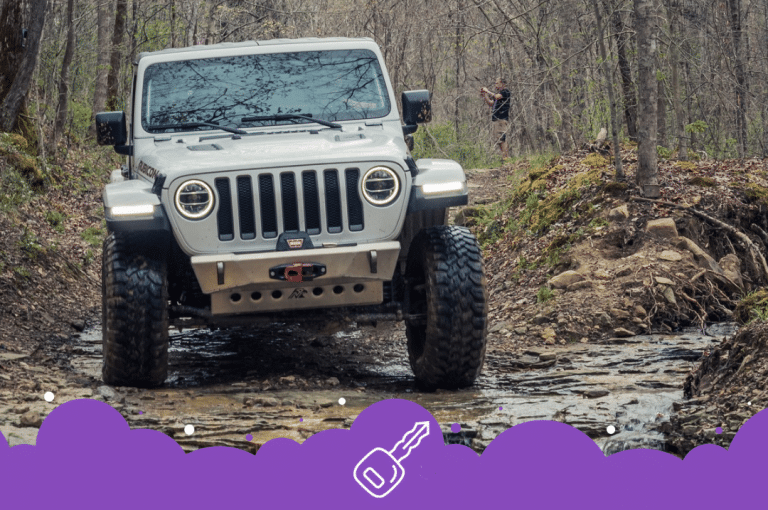 White Jeep wrangler driving in the mud in a forest