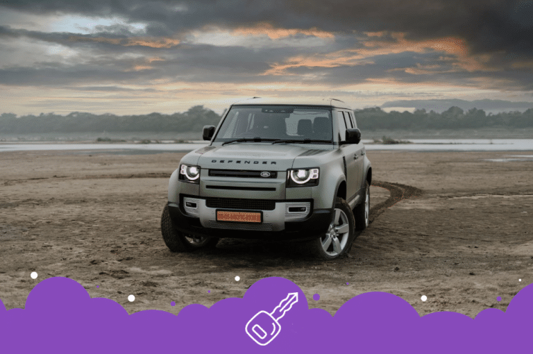 Gray defender parked infront of mountains