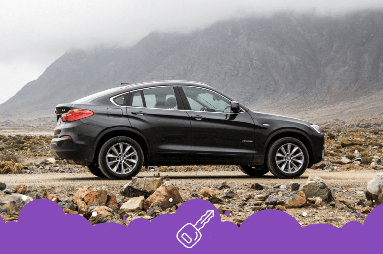 Black bmw x4 parked on road infront of foggy mountains