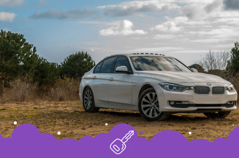 White bmw 3 series parked on dirt road infront of trees
