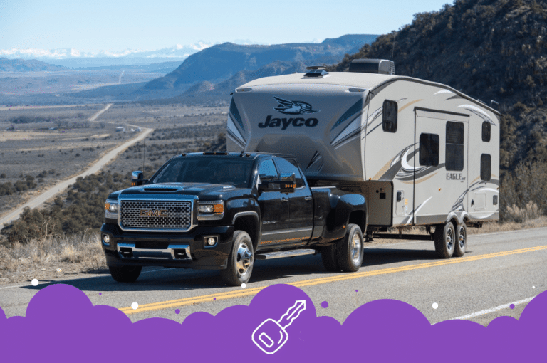 Black gmc truck towing trailer infront of mountains